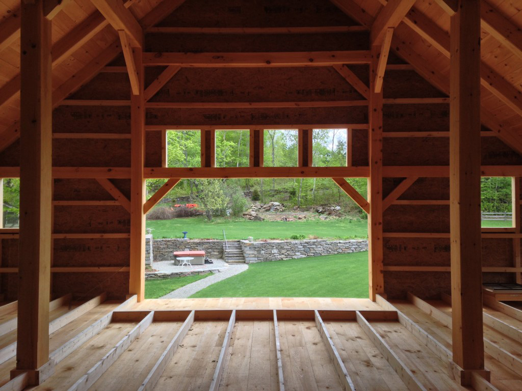 View of the outdoors from the interior of a timber frame barn