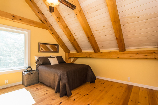 Bedroom with a titled ceiling in a timber frame dutch saltbox