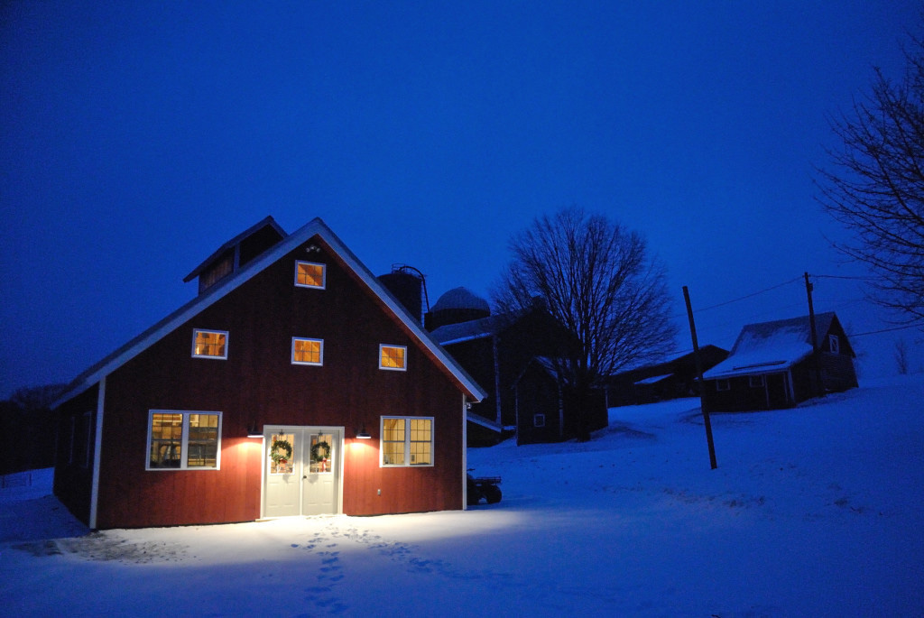 Finished exterior of a timber frame sugar house at night in the snow